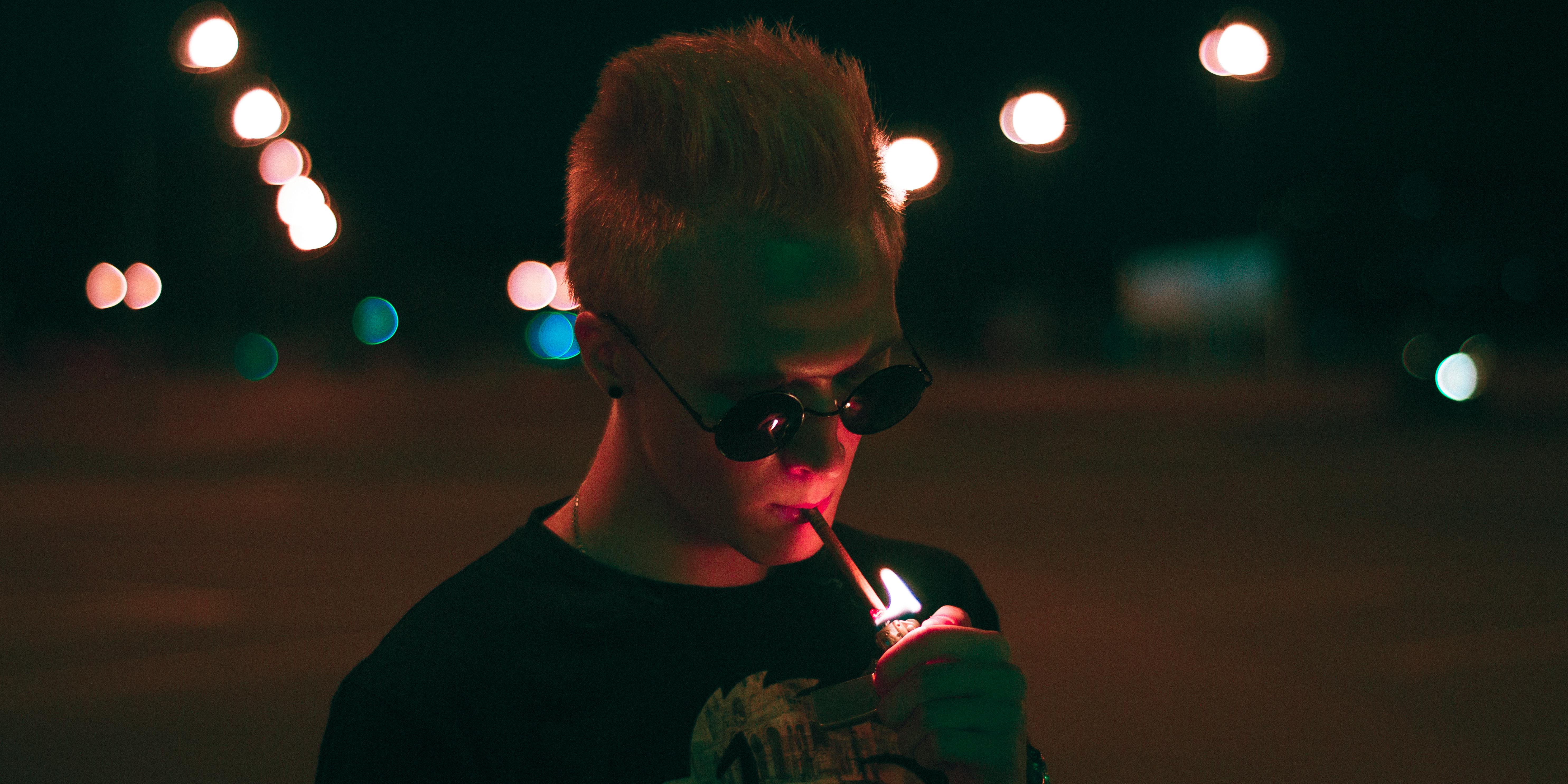 blonde man lighting a cigarette